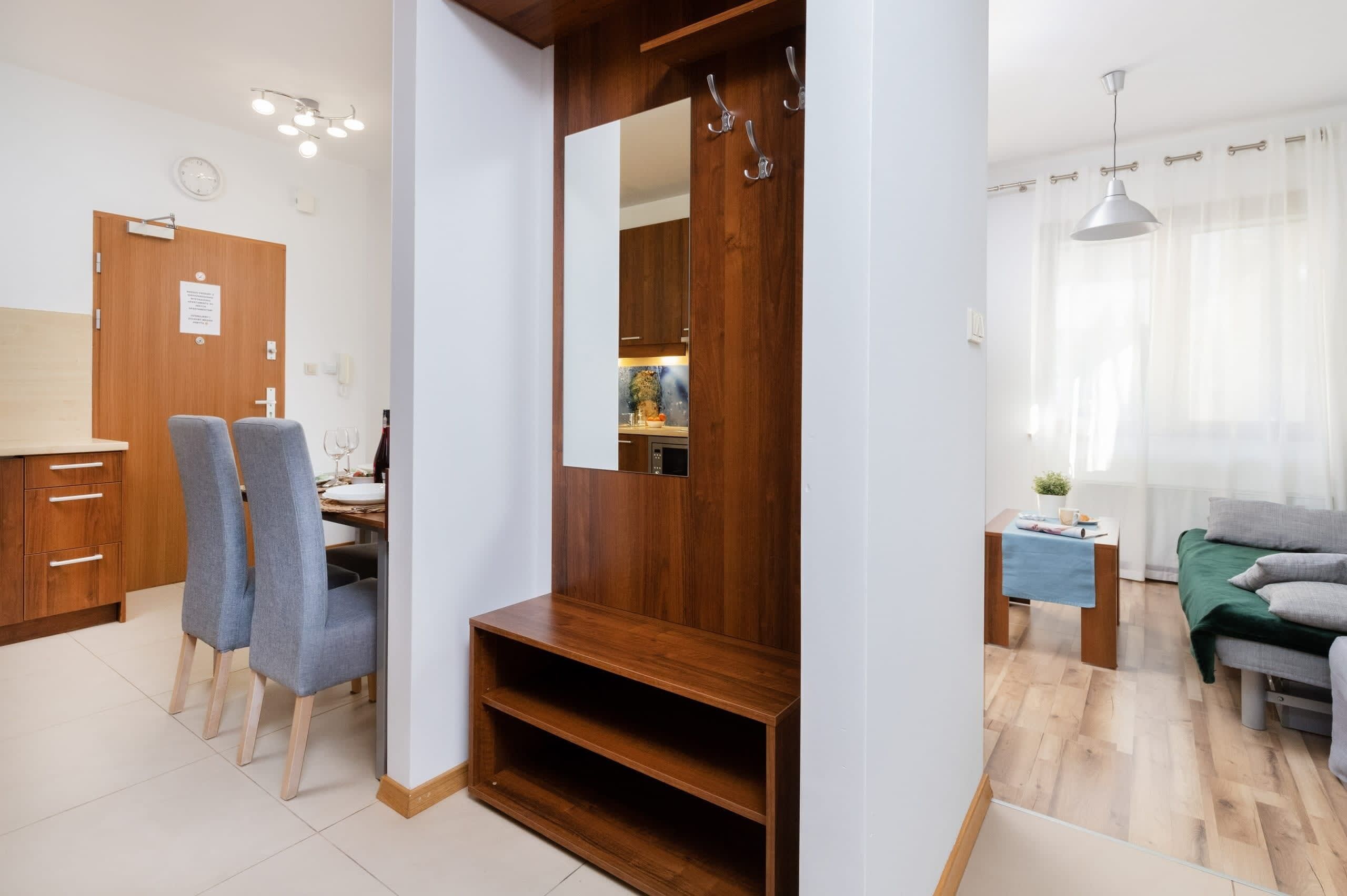 A modern living room with a wooden entertainment unit, a dining area with chairs, a sofa, and a small table with a plant.