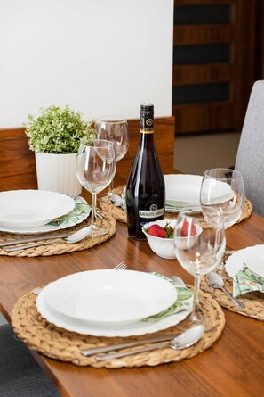 Une table à manger dressée avec des assiettes, des couverts, des verres à vin et une bouteille de vin.