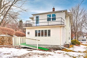 Een huis met twee verdiepingen, een balkon, een groene hellingbaan en een stenen muur.