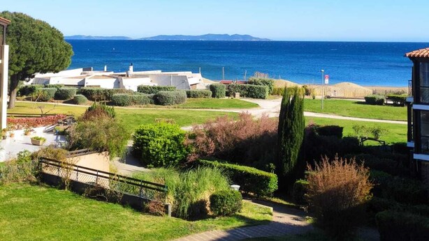Una proprietà costiera con vista aperta sul mare, un vialetto lastricato e giardini curati.