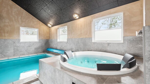 Un espace piscine intérieur moderne comprenant un jacuzzi, une petite piscine et un coin salon.