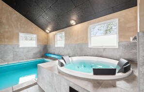 A modern indoor pool area with a hot tub, a small pool, and a seating area.