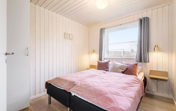 A bedroom with a bed, a window, and two bedside tables with lamps.