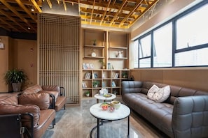 A modern lounge area with leather sofas, a coffee table, and a bookshelf. - Shenzhen Aige Hotel (Clothing Wholesale Market Nanyou Metro Station Store) (Shenzhen)
