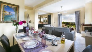 A dining area with a table set for four, a vase with flowers, and a painting on the wall. - Rose Villa in Svoronata (Kefalonia)