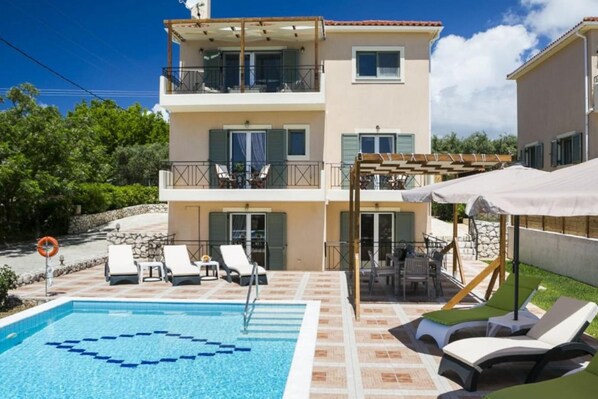 A two-story building with a swimming pool, outdoor seating, and a pergola.