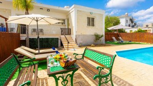 A poolside area with a table set for a meal, a bench, and a lounge chair.
