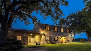 A stone building with multiple windows and a well-lit entrance.