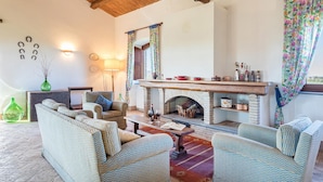 A cozy living room with a fireplace, wicker furniture, and a view of the outdoors.