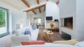 Un amplio salón con un sofá blanco, una mesa de centro y una chimenea.