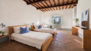 Camera da letto con due letti, soffitto in legno, una finestra e un termosifone.