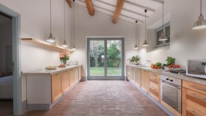 A modern kitchen with a large sliding glass door leading to a garden, wooden cabinets, and pendant lighting. - Villa Carmeli 12 2 in Acquapendente (Acquapendente)