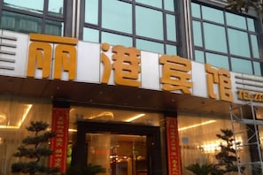 A hotel entrance with large signage, a glass facade, and a modern architectural design.