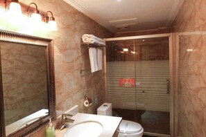 A bathroom with a marble sink, a large mirror, a glass shower enclosure, and a towel rack. - Ligang Hotel (Xishui)