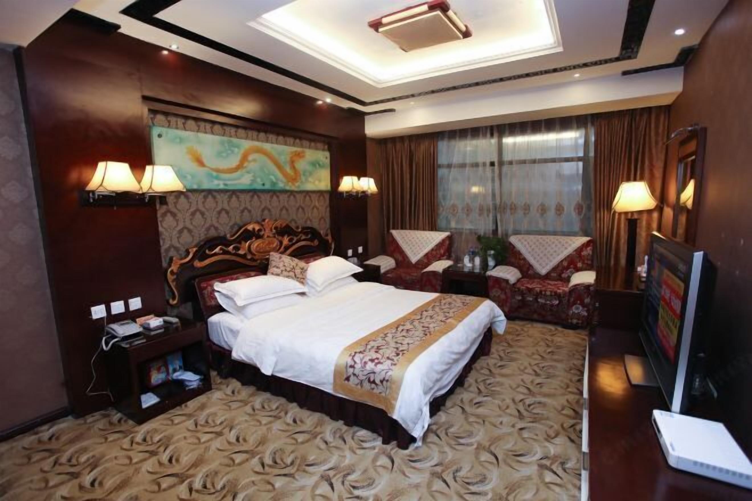A hotel room with a large bed, a desk with a computer, and a TV.