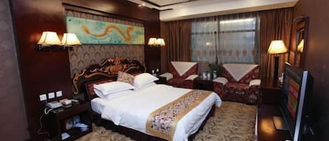 A hotel room with a large bed, a desk with a computer, and a TV.
