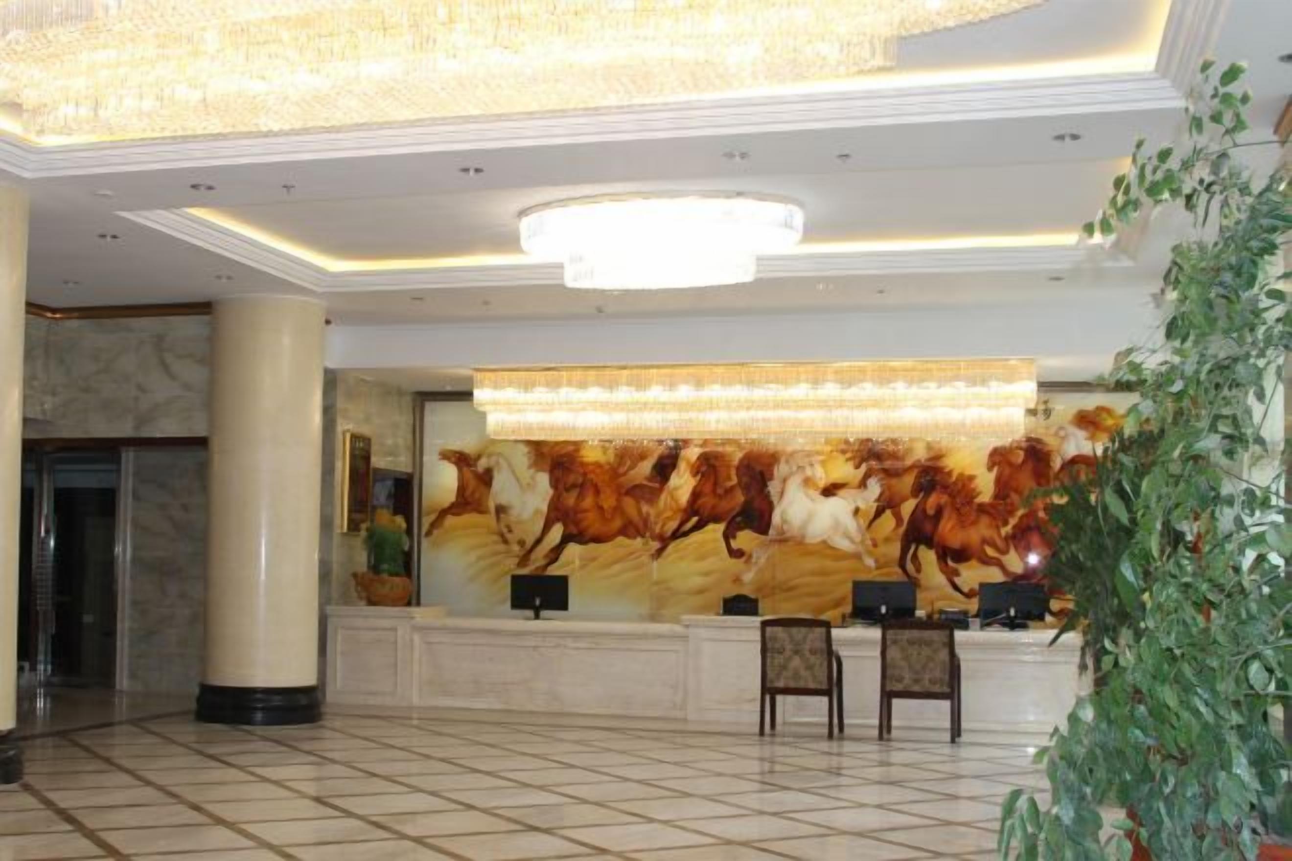 A lobby with a reception desk, a large chandelier, and a marble floor.