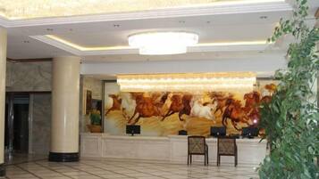 A lobby with a reception desk, a large chandelier, and a marble floor.