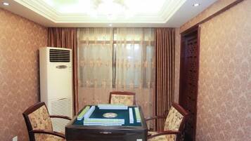 A room with a table set for four, a large air conditioner, and a decorative window with curtains.