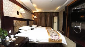 A hotel room with a large bed, bedside tables, a TV, and a wardrobe.