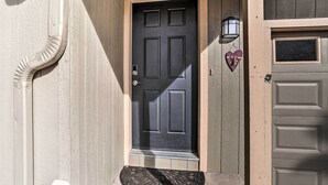 A front door with a black panel, a small step leading up to it, and a heart-shaped decoration on the wall to the right. - Mount Shasta Escape w/ Balcony ~ Walk to Dtwn (Mount Shasta)
