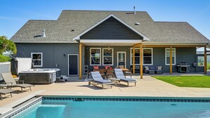 Una casa residenziale con piscina, area relax esterna e vasca idromassaggio.