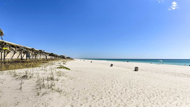 Ein weiter Sandstrand unter blauem, wolkenlosem Himmel.