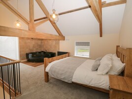 Un dormitorio con cama de madera, ventana con vistas, bañera y estructura de techo de madera.