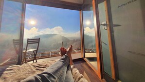 Een kamer met een groot raam en uitzicht op bergen en een heldere lucht.