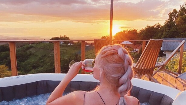 Iemand in een bubbelbad met uitzicht op een zonsondergang.