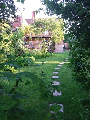 Stroll through the lush garden to the charming house with a brick chimney.