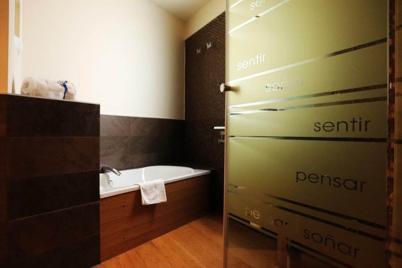 A modern bathroom with a bathtub, a towel on the edge, and a glass door with the word 'sentir' repeated.