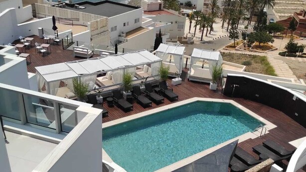 Un espace piscine aménagé sur le toit, offrant une vue sur l’océan et le paysage urbain.