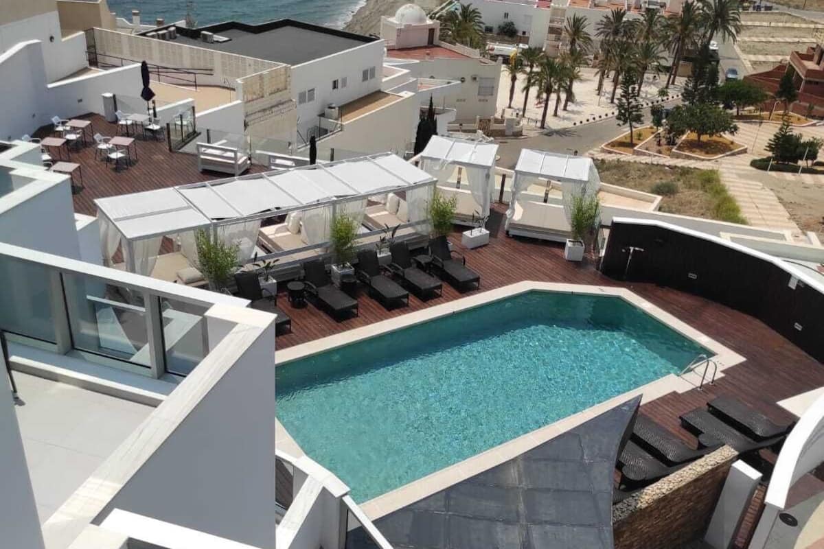 A rooftop pool area with a view of the ocean and a cityscape.