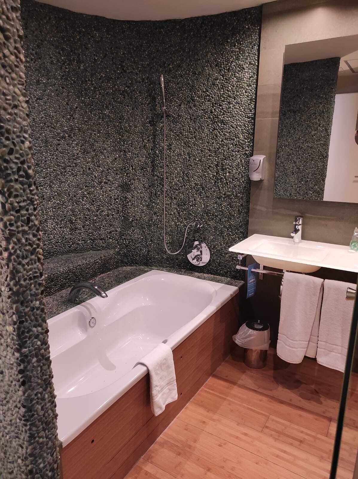Uma casa de banho moderna com uma banheira independente, uma pia e um espelho.