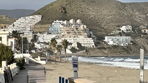 Une ville côtière avec des bâtiments construits sur une colline, une plage et un panneau indicateur.