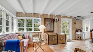 Uma sala de estar aconchegante com um sofá listrado, um baú de madeira e janelas amplas.