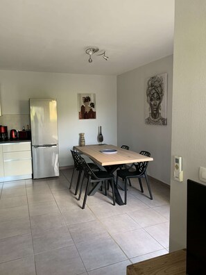 Una cuina moderna amb nevera, taula de dinar amb caires i màquina de cafè.