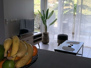 Habitació amb televisió, una planta, un plat de fruita i una taula amb suport per a la tassa.