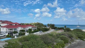 A coastal residential area with houses, a beach, and a sailboat. - 2-room apartment with a veranda and a small garden (La Savane)