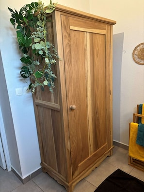 Un armario de madera con puerta y una ventana pequeña, un interruptor fijado a la pared y una decoración mural tejida.