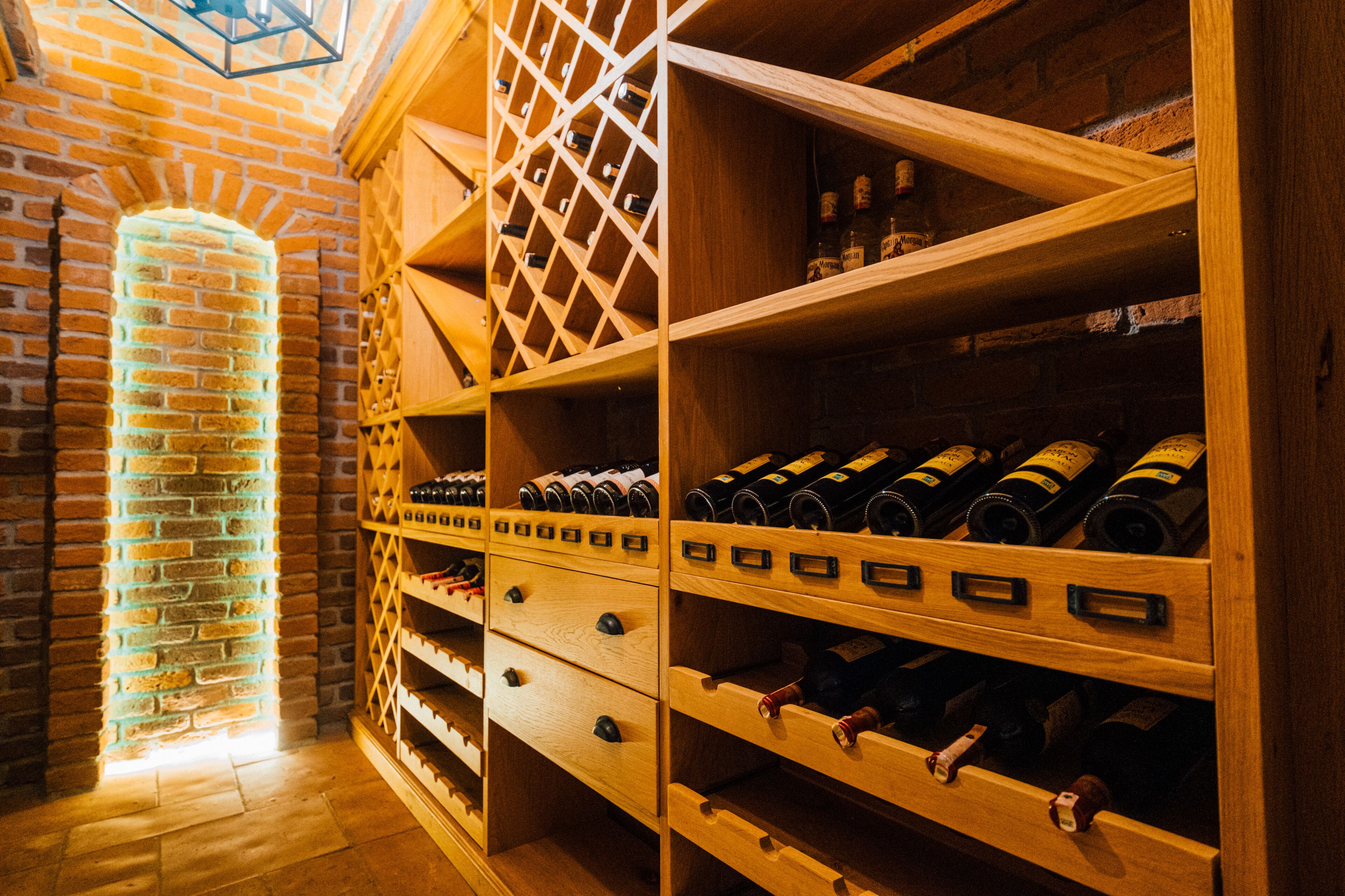 Una bodega con estantes y cajones de madera, pared de ladrillo y tragaluz.