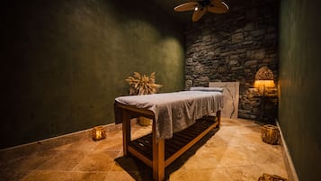 Relax in a serene spa room with a wooden bench, rustic stone wall, and ceiling fan for a tranquil ambiance.