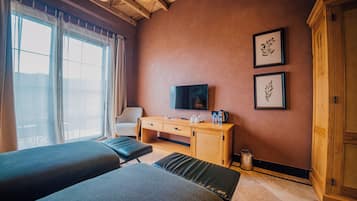 A hotel room with two beds, a desk with a TV, and framed pictures on the wall.