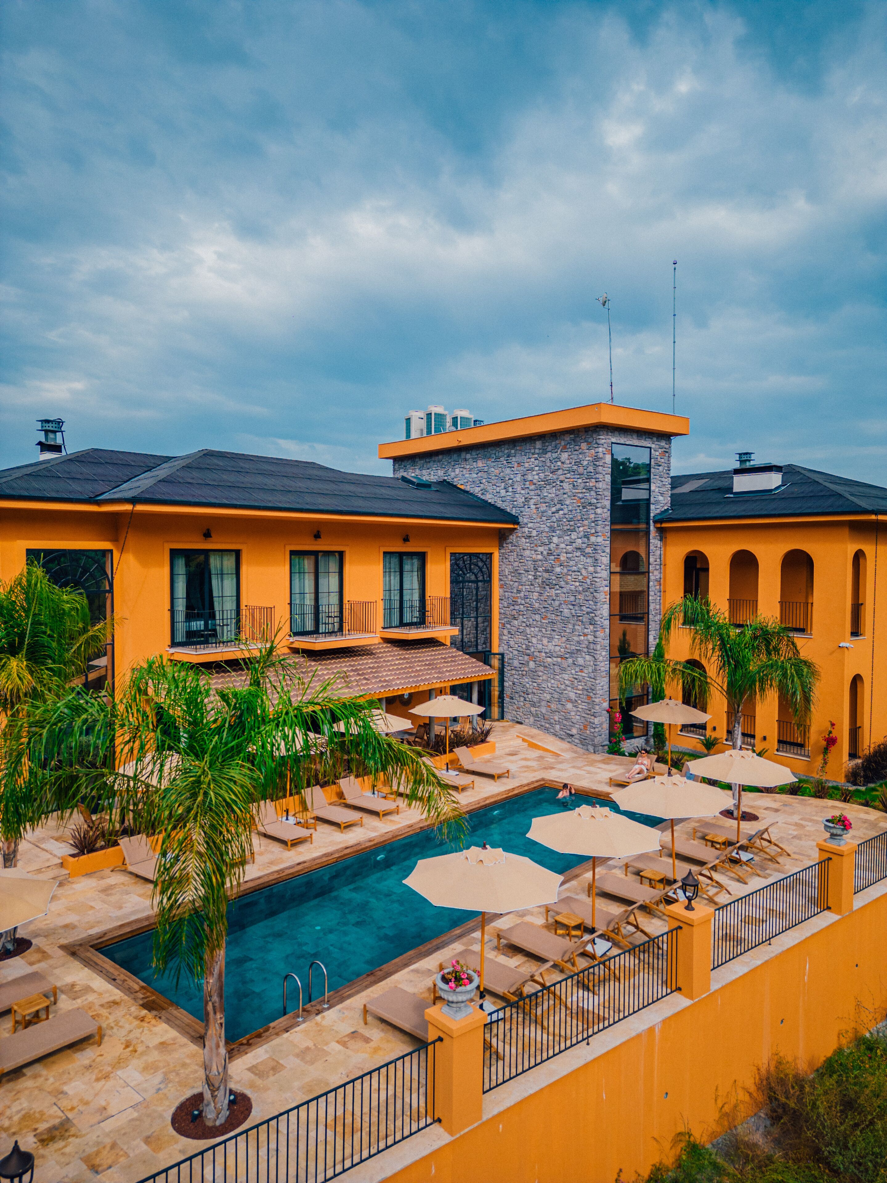A hotel with a swimming pool, outdoor seating, and a stone facade.