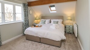 Ein Schlafzimmer mit einem großen Bett, zwei Nachttischen, einem Oberlicht und Blick auf Bäume.