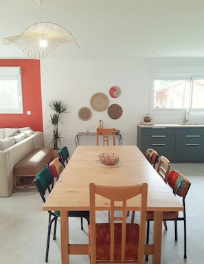 Un espace repas comprenant une table en bois, des chaises et un luminaire suspendu.