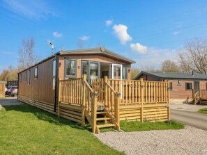 A wooden mobile home with a porch and a staircase leading to a deck. - Birch Lodge (Carnforth)