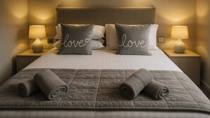 A neatly made bed with two pillows, each with the word "love" embroidered on them, and two bedside lamps on either side. - Birch Lodge (Carnforth)