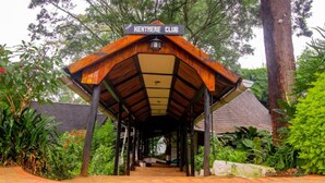 Une structure abritée, portant l’inscription « KENTMERE CLUB », avec un toit en bois et un pilier central, entourée d’une végétation luxuriante.